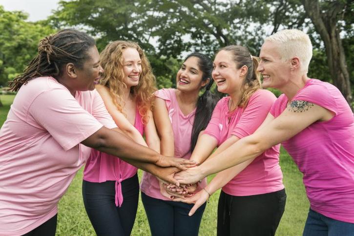 Women in pink shirts with hands together